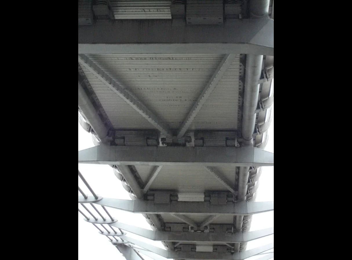 The underside of the Millennium Bridge deck seen from below, showing the V-shaped steel bracing between the cross-arms.