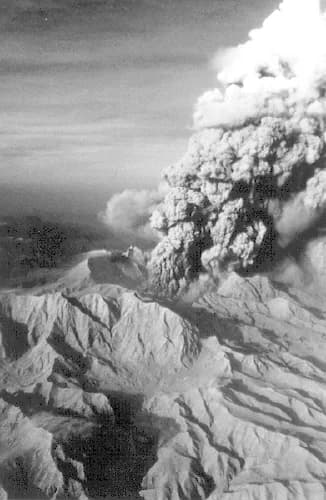 Grey ash and gas column rising from Mount Pinatubo above ridged mountains, Philippines, June 1991.