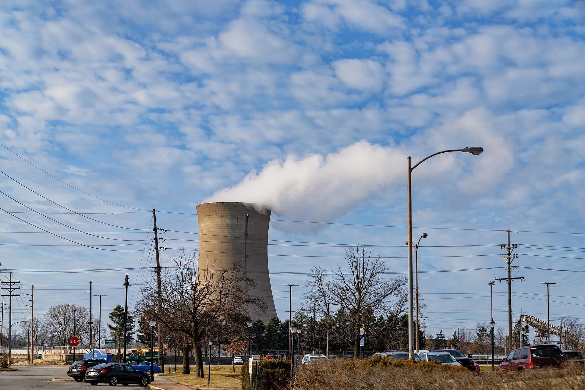 A concrete cooling tower at Michigan City Generating Station, Indiana, releasing steam. Its walls curve in to a narrow waist near the top and flare out towards the base and the rim.