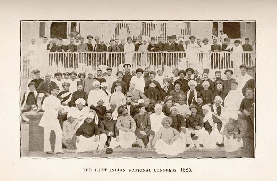 Black and white group photograph of several dozen men, most in Indian dress with turbans or caps and some in European suits, seated and standing in rows.