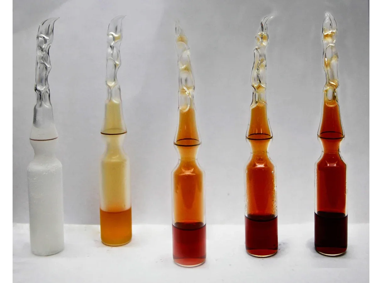 Five identical sealed glass ampoules of nitrogen dioxide and dinitrogen tetroxide. From left to right at −196 °C (white solid), 0 °C (pale yellow), 23 °C (orange-brown), 35 °C and 50 °C (deep red-brown).