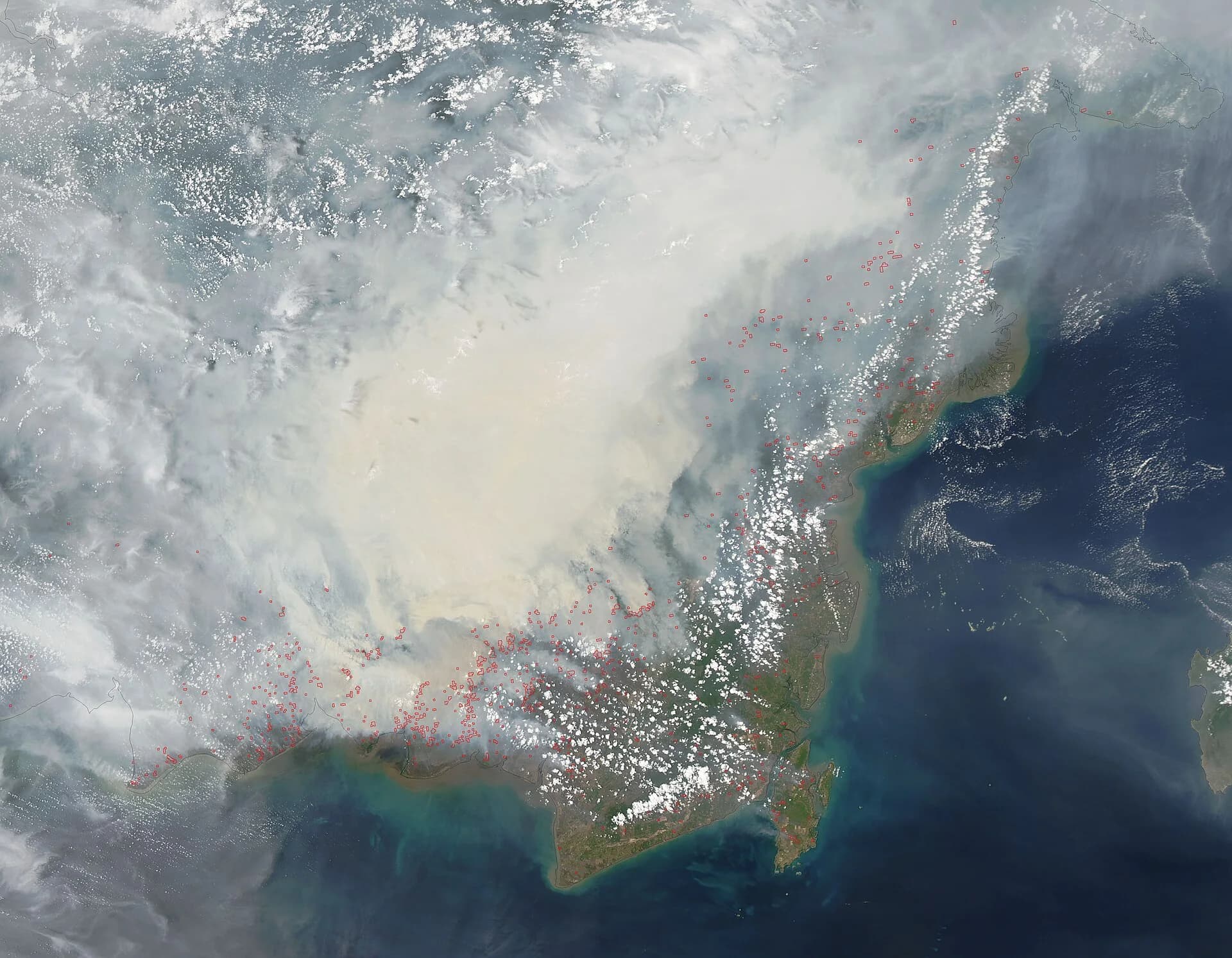 Satellite image of southern Borneo on 27 October 2015: a thick pale smoke plume covers the centre of the island, with hundreds of small red outlines marking active fires along the south coast of Central Kalimantan.