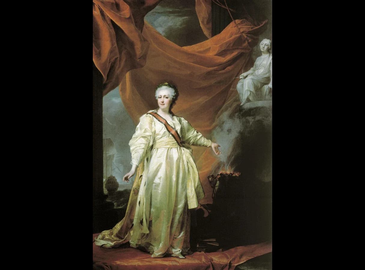Full-length painted portrait of Catherine II in a white dress, red sash, ermine-lined robe and laurel wreath, standing under a red curtain and gesturing towards an altar on which a small fire burns. A statue of the goddess of Justice stands on a pedestal behind the altar; a sailing ship is…