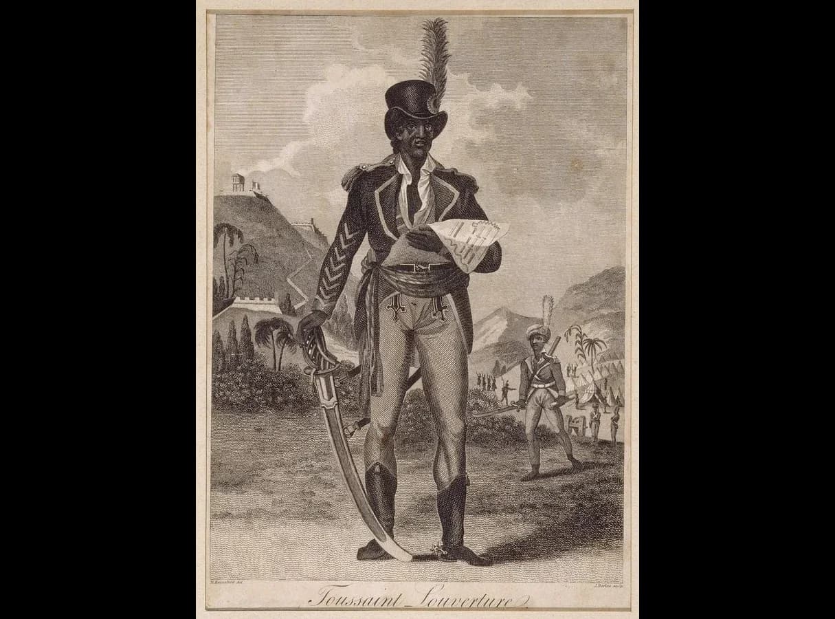 Engraving of Toussaint Louverture standing in a general’s uniform with a plumed hat, sash and curved sword, holding a document, with a fort on a hill and soldiers and tents behind him.