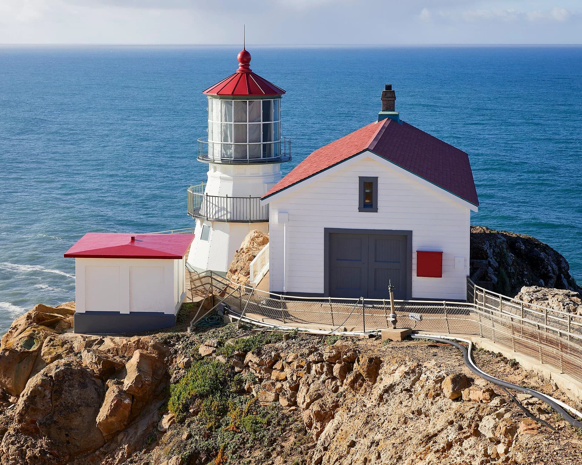 Point Reyes lighthouse, a small white lighthouse on a rocky headland above the Pacific Ocean in California.