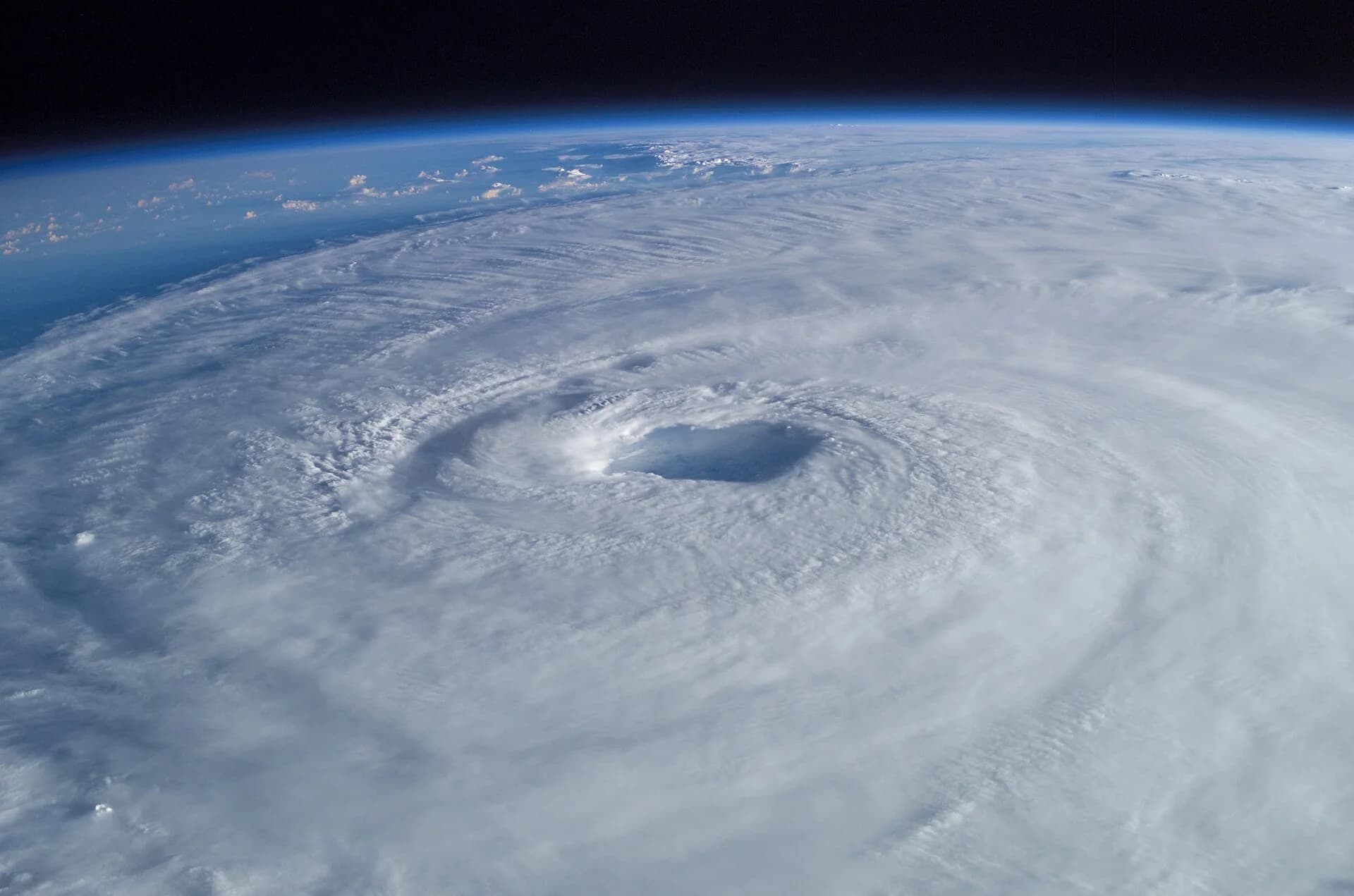 Hurricane Isabel photographed from the International Space Station: a vast spiral of cloud bands around a clear, circular eye, with the curve of the Earth behind.