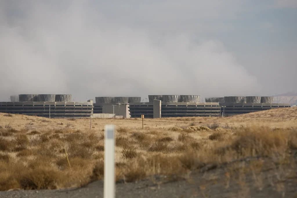 Rows of low mechanical-draft cooling towers at the Columbia Generating Station in the dry landscape of Washington State, USA, with a large cloud of water vapour rising above them.