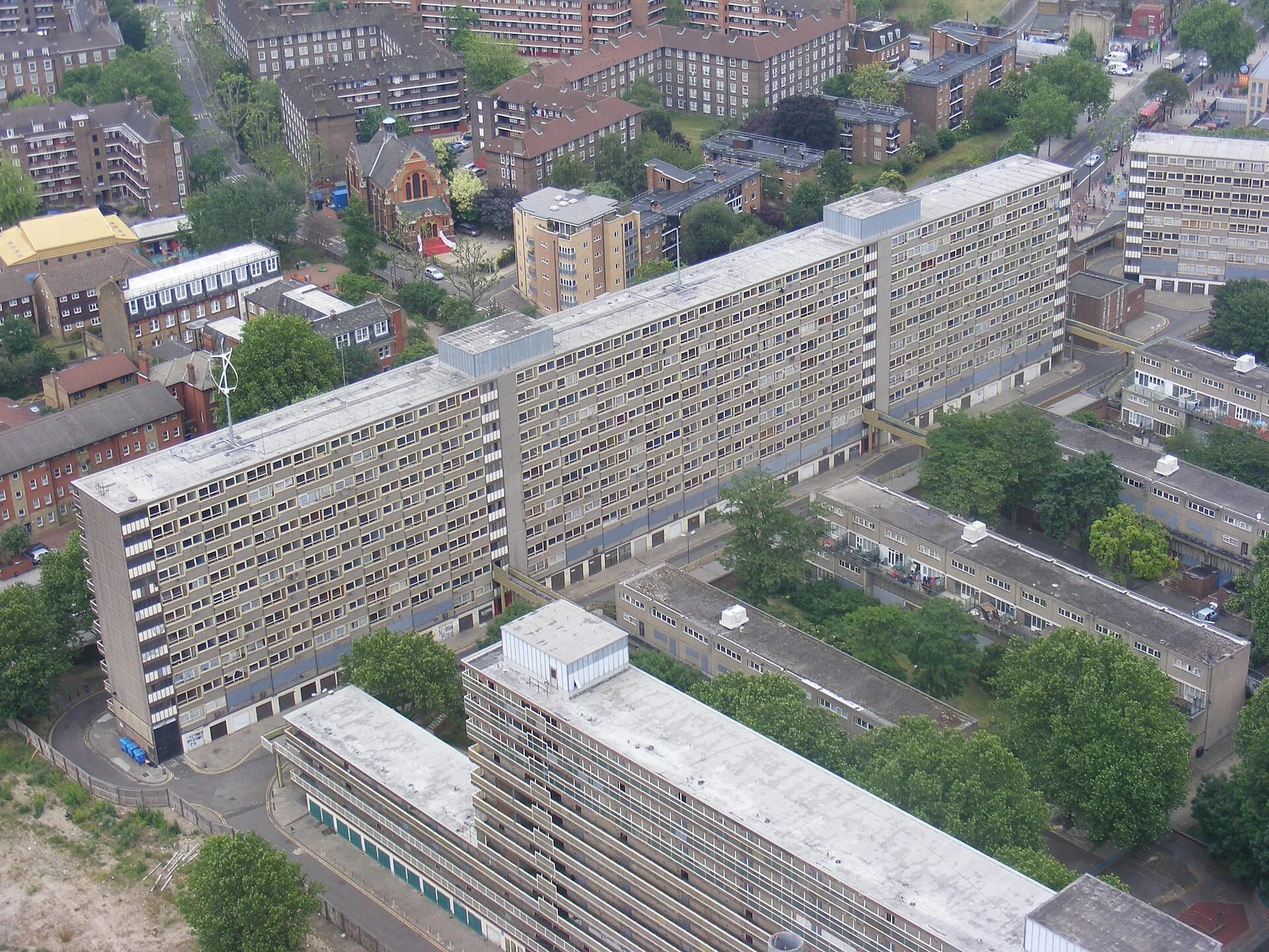 Aerial photograph of the Heygate Estate in Southwark, London, before demolition: long concrete slab blocks of flats up to about 12 storeys with walkways between them and mature trees in the courtyards.