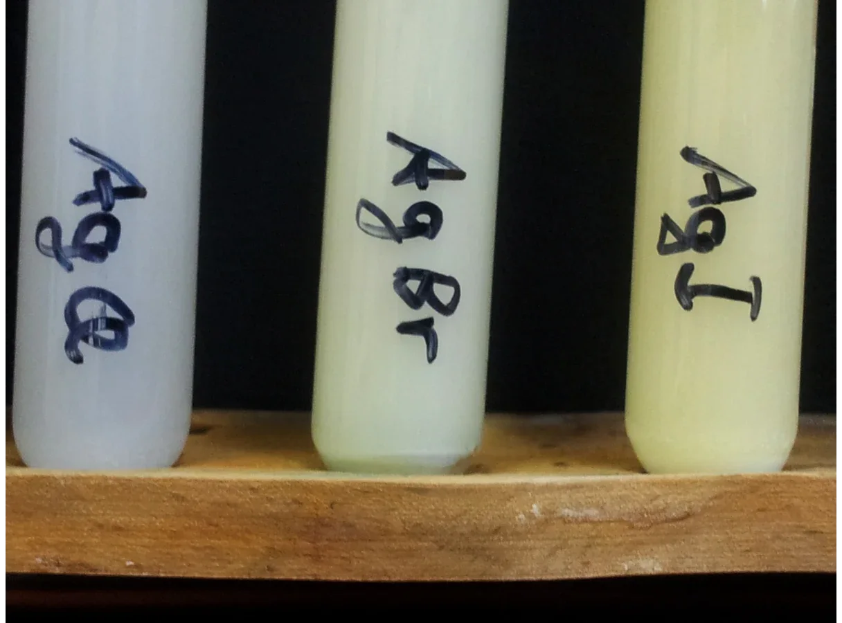 Three test tubes of precipitate, from left to right: silver chloride (white), silver bromide (cream) and silver iodide (pale yellow).