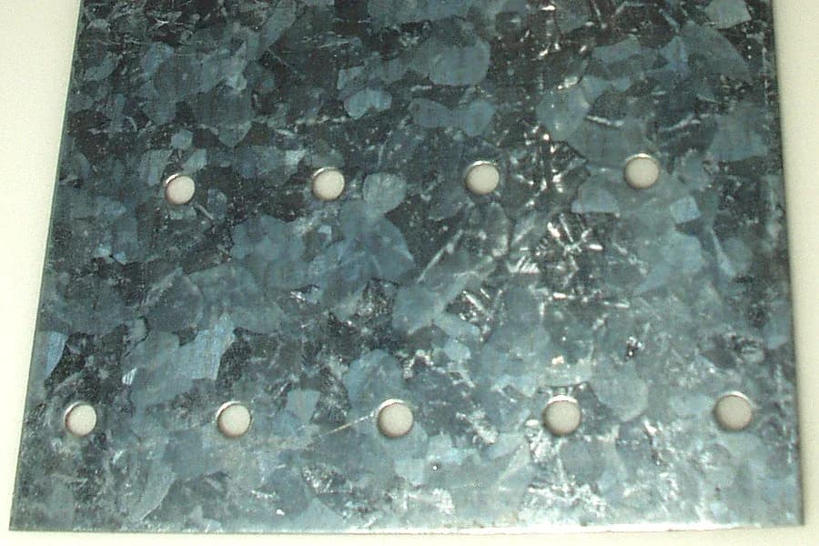 A hot-dip galvanized steel plate with a silvery zinc coating that has crystallized into large flat patches called spangle.