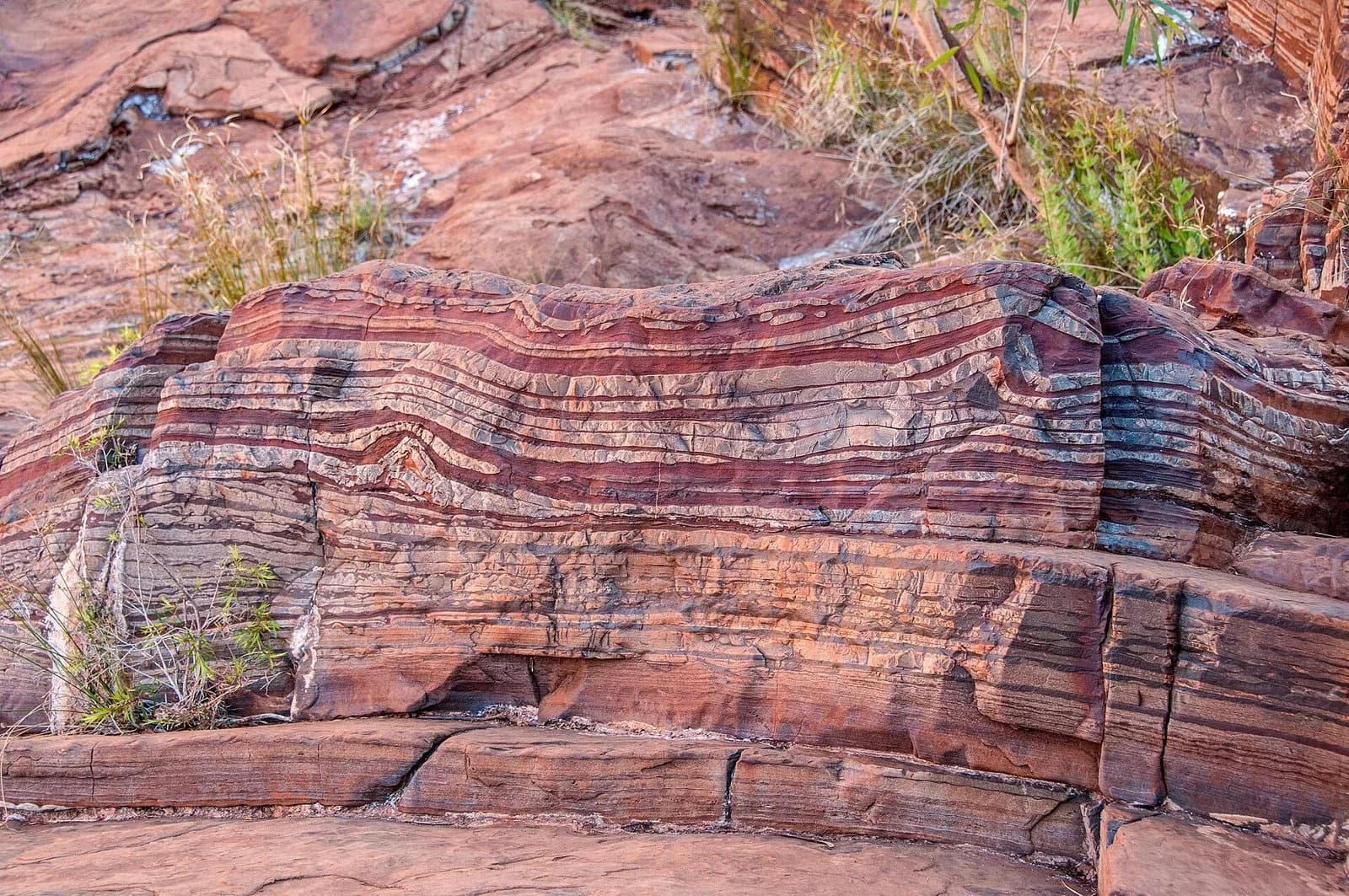 Cliff of layered rock at Dales Gorge, Western Australia: thin, alternating dark red-brown and paler bands of banded iron formation stacked horizontally.