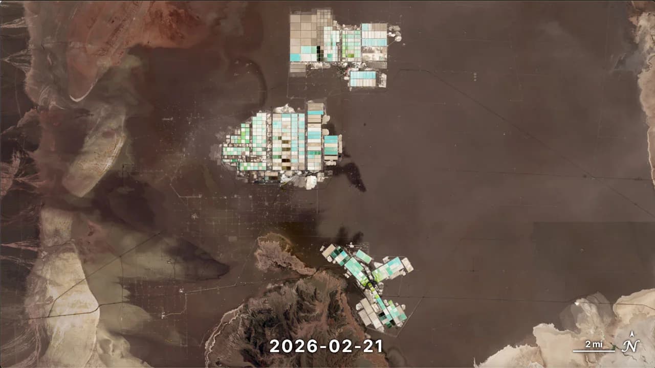 Satellite image of the Salar de Atacama on 21 February 2026: three clusters of rectangular evaporation ponds in shades of white, turquoise and green on the brown salt crust, with mountains to the west and a 2-mile scale bar.